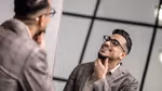 Homme en veste à carreaux souriant et regardant son reflet dans le miroir.